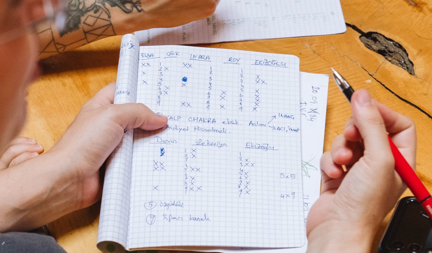 Hands holding a notebook of call notes and a red pen over a table