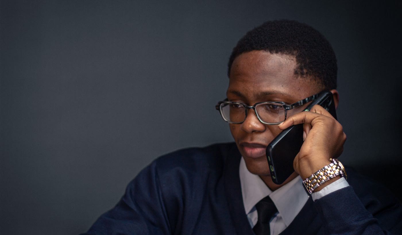 A man in glasses and a tie listening closely on a phone call