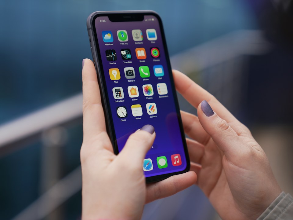 Two hands holding a smartphone showing the home screen