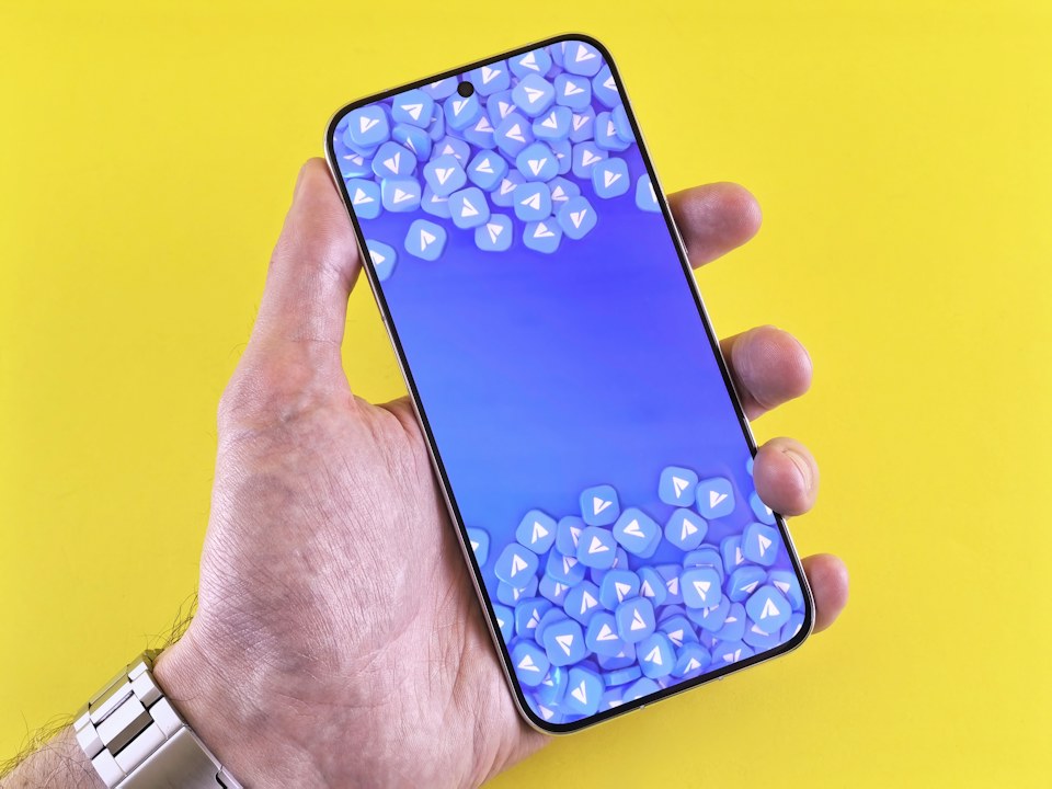 A hand holding a smartphone against a yellow background