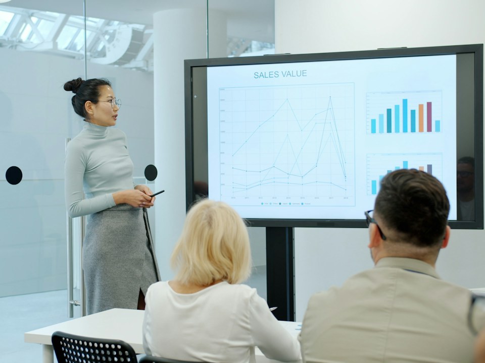 A woman presenting a bar chart on a screen to colleagues