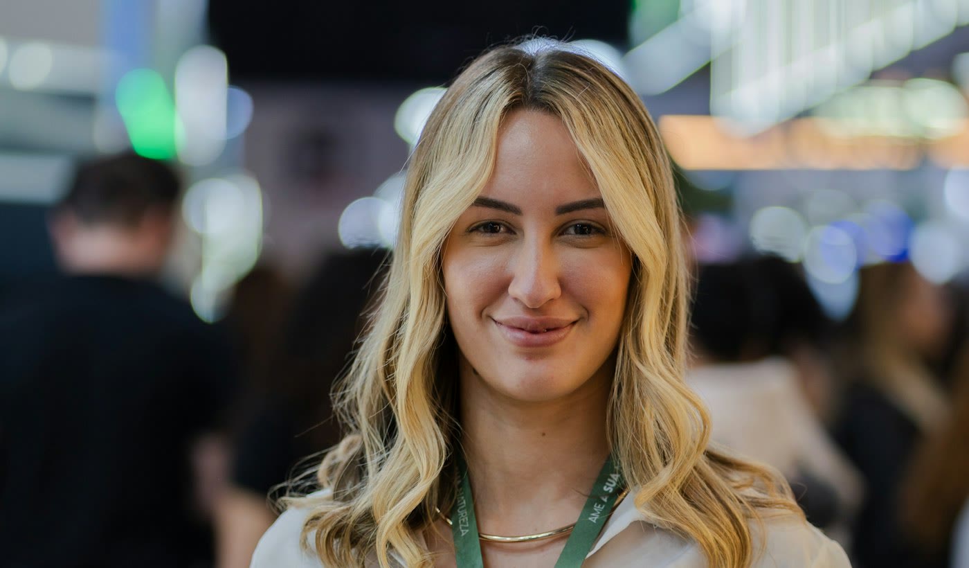 A woman with a conference badge lanyard smiling at a business event