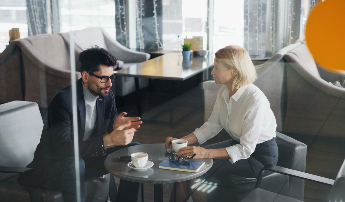 A man and a woman talking over coffee in an office lounge