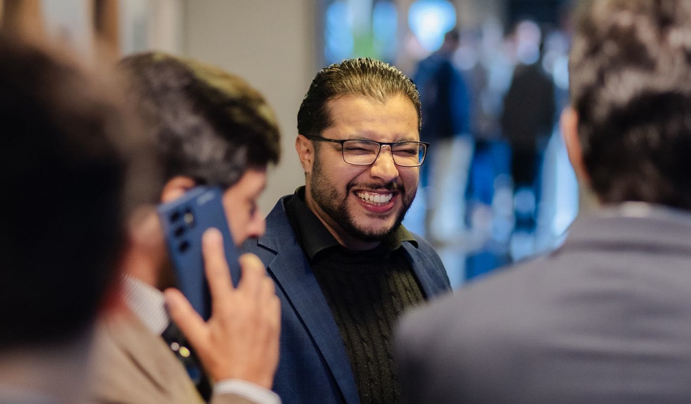 Two professionals laughing together at a networking event while one takes a call