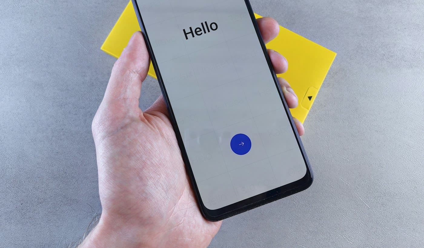 A hand holding a phone with the word Hello on its screen